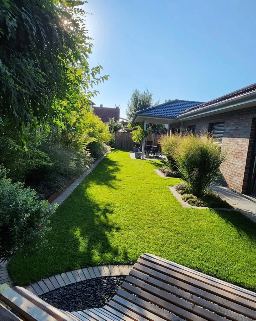 Garten mit Rasen, Gräserbeet und Holzbank