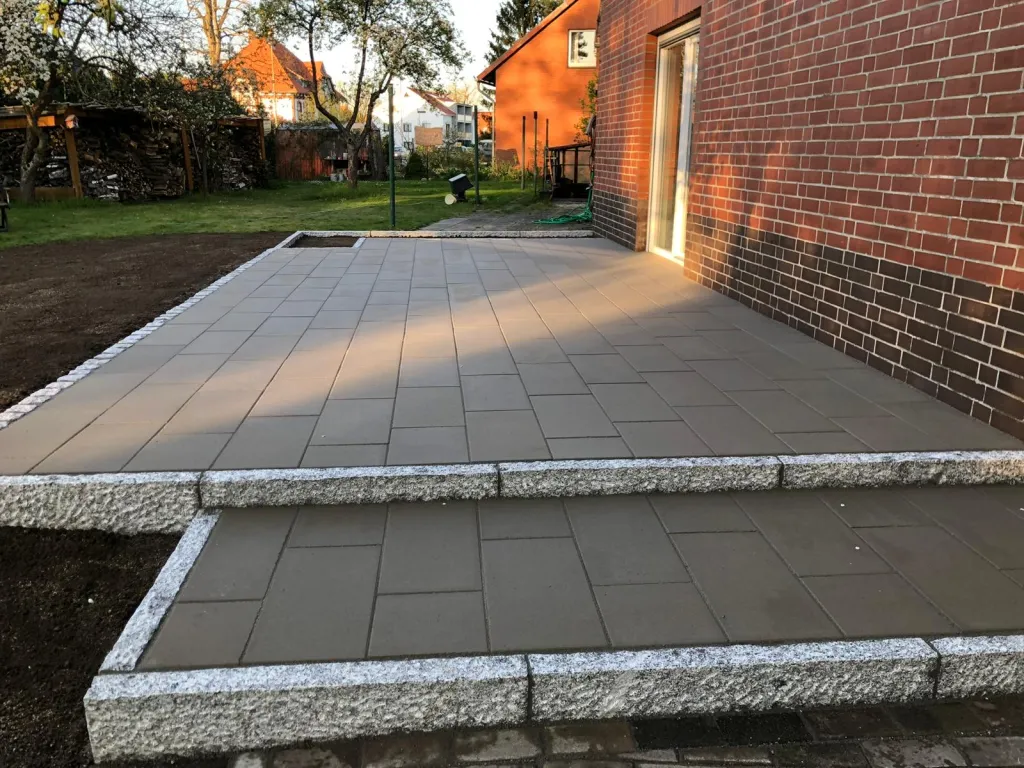 Gepflasterter Innenhof mit Stufe an einem Klinkerhaus