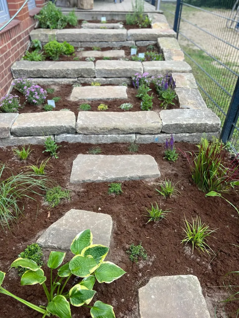 Hangbeet mit Natursteinstufen und Trittplatten