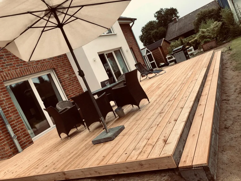 Holzterrasse mit Esstisch und Sonnenschirm