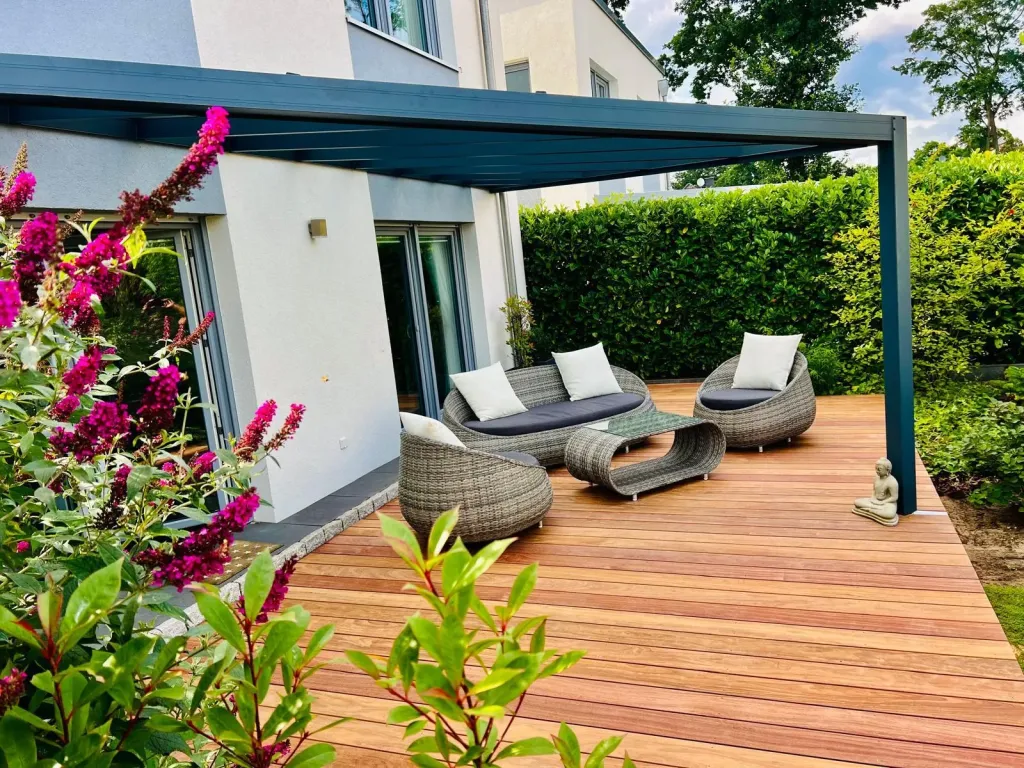 Holzterrasse mit Loungemöbeln unter einem Sonnensegel