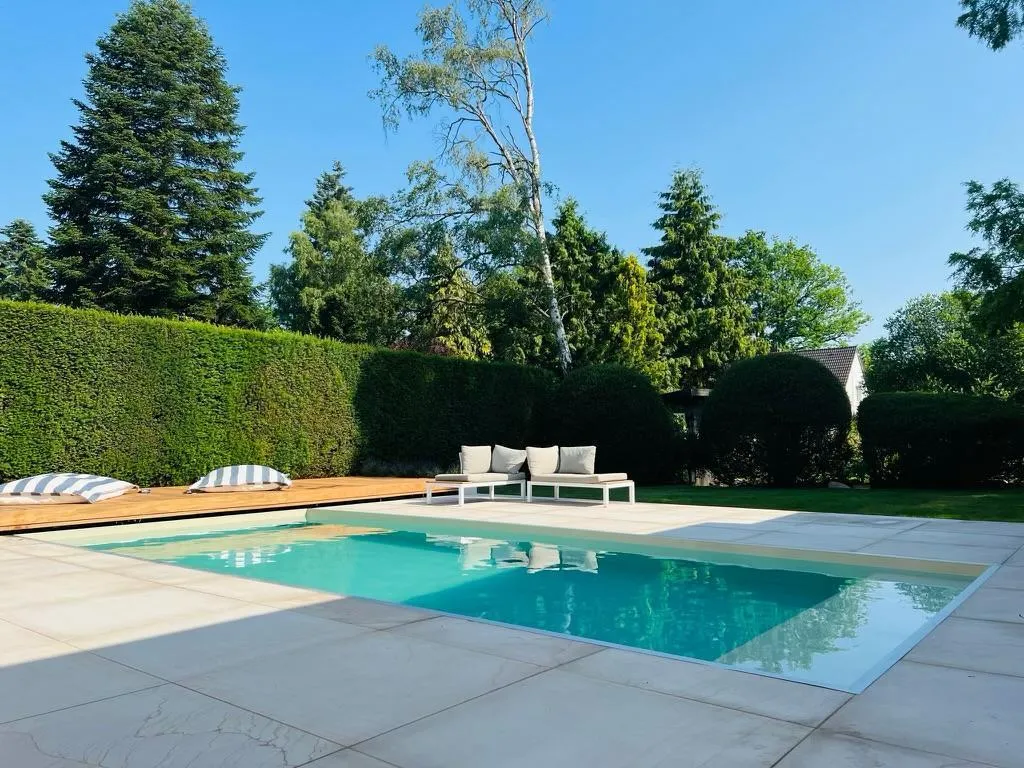 Pool mit heller Plattenumrandung und Loungemöbeln