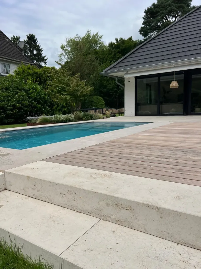 Pool mit Holzdeck und Natursteinstufen an einem Bungalow