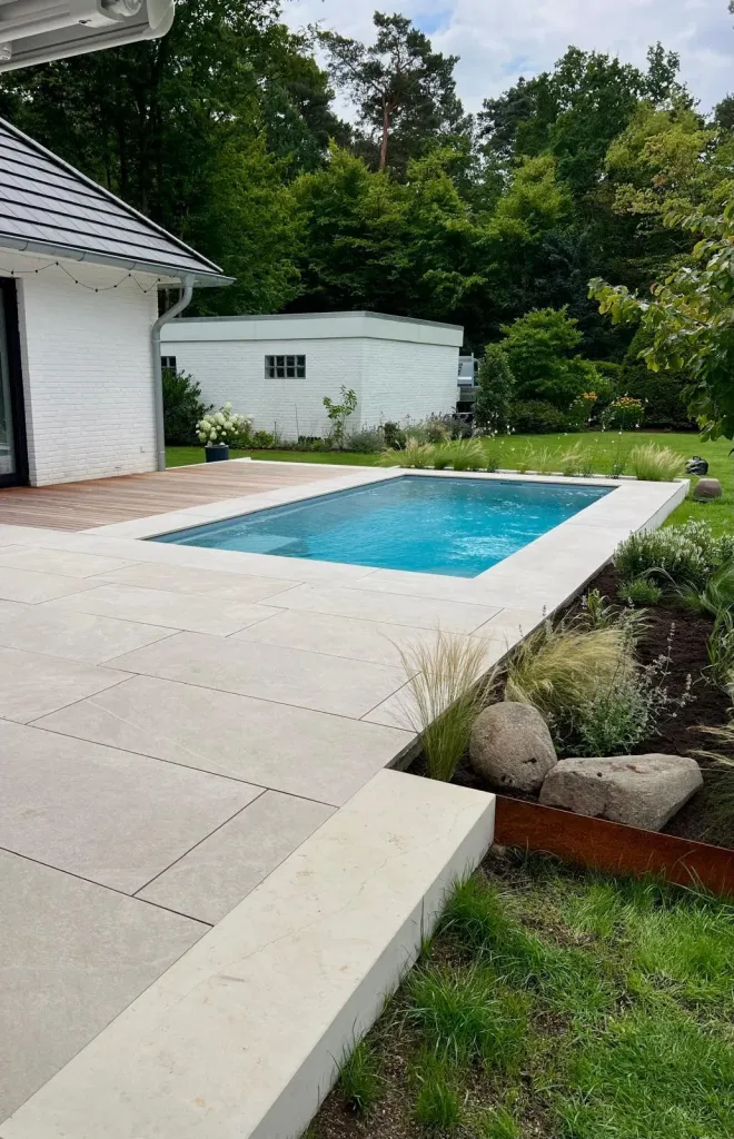 Pool mit Natursteinplatten, Findlingen und Cortenstahl-Beet