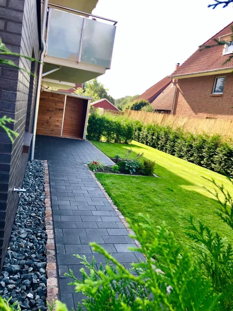 Schmaler Weg mit Kies und Rasen am Haus