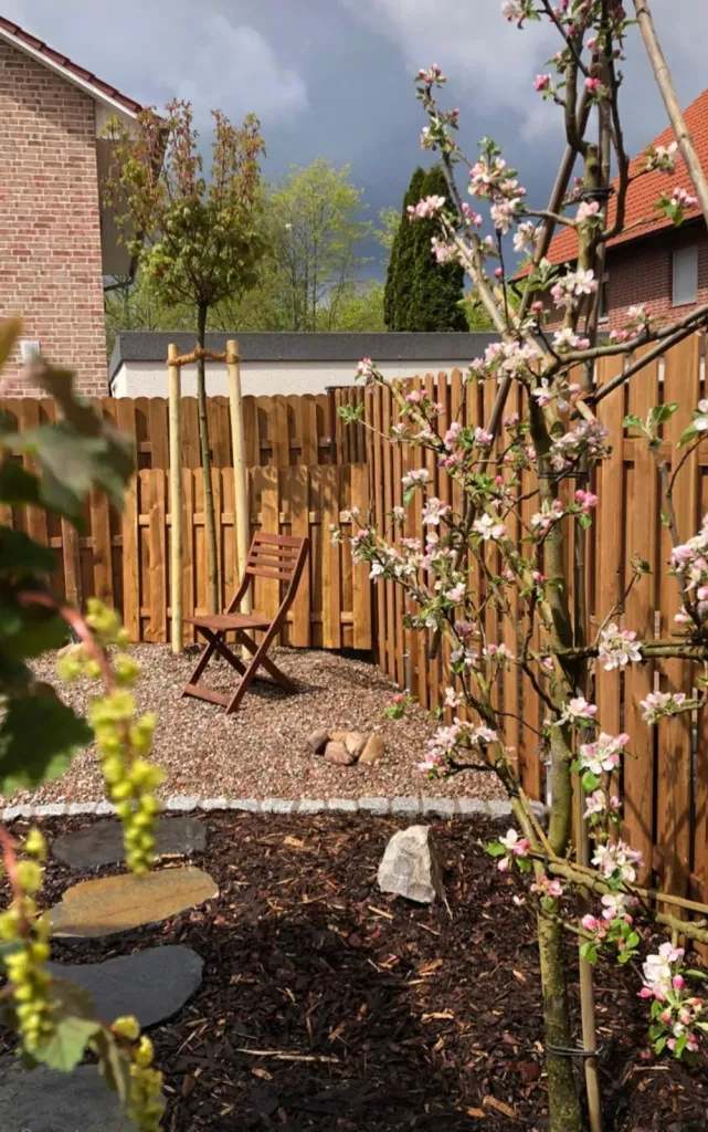 Sichtschutz aus Holz mit Kiesfläche und Gartenstuhl