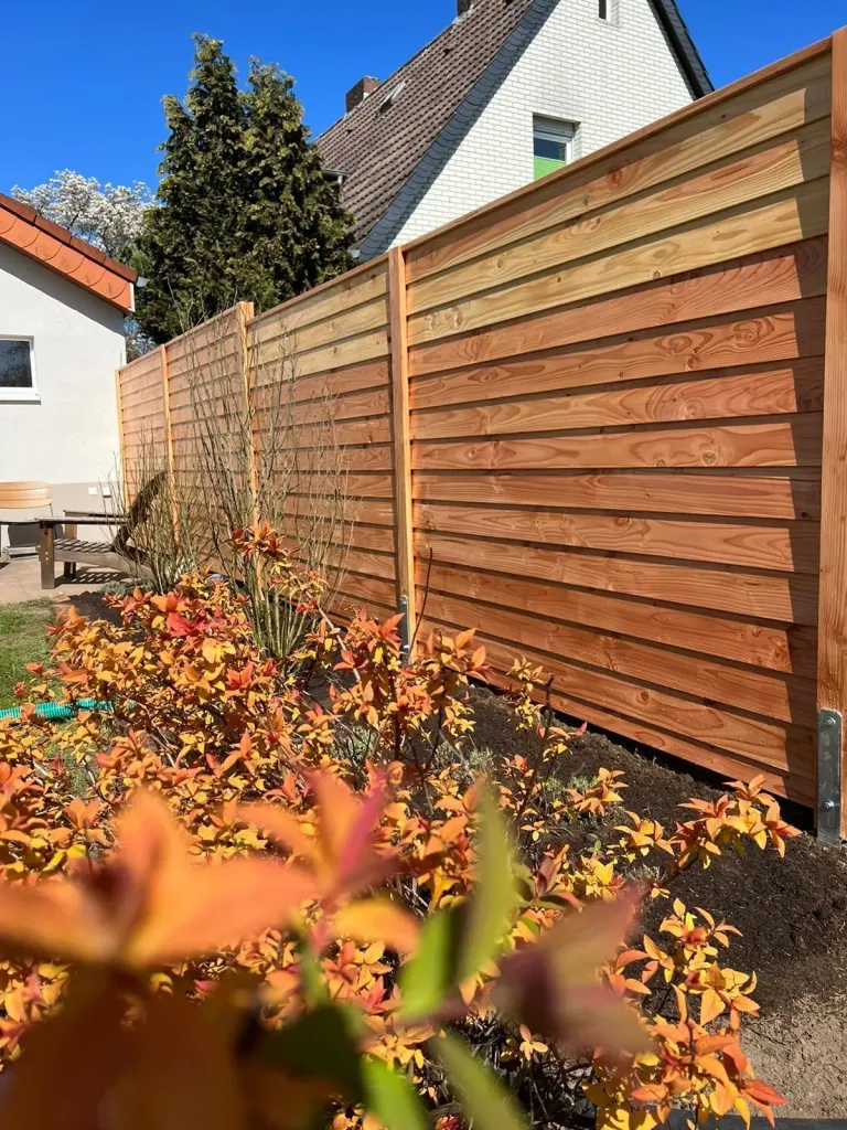Sichtschutzzaun aus Holz mit Spiersträuchern