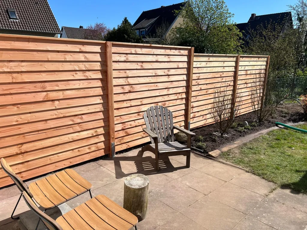 Sichtschutzzaun aus Holz mit Terrasse und Gartenstuhl