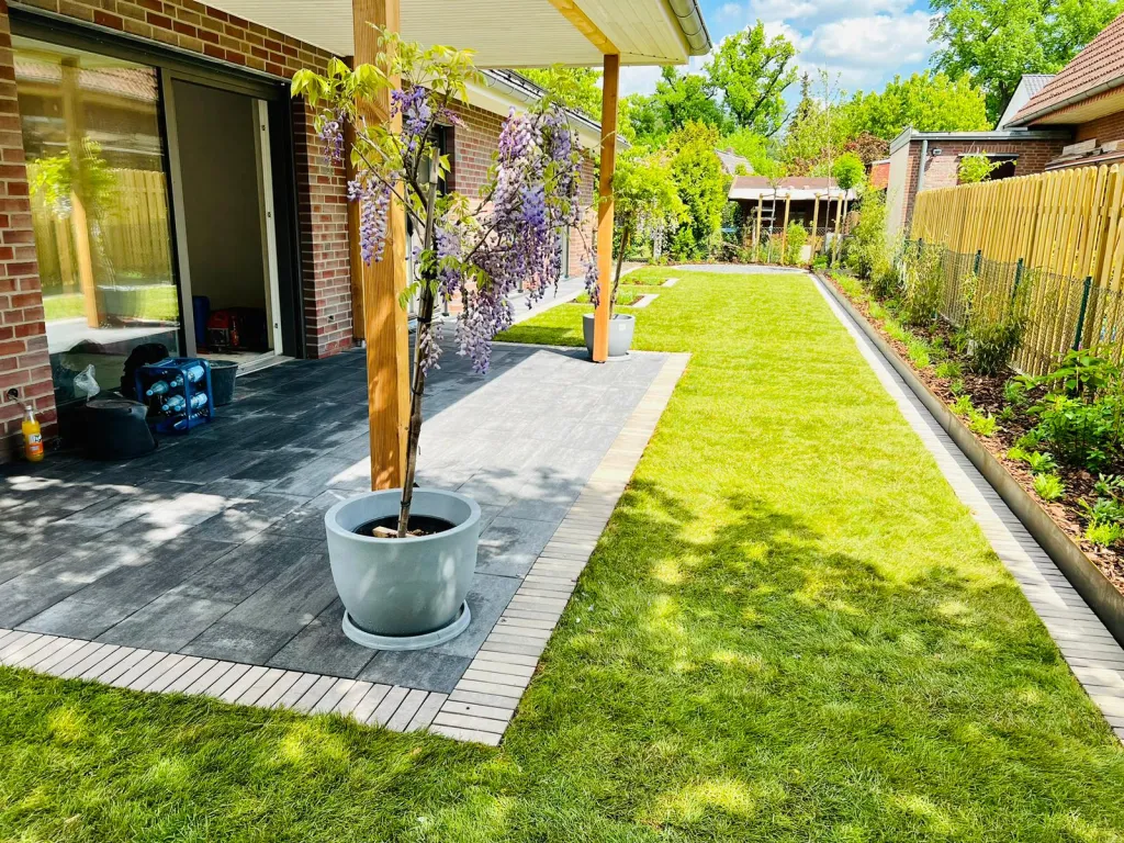Terrasse aus großen Platten mit Pflanzkübel und neuem Rasen