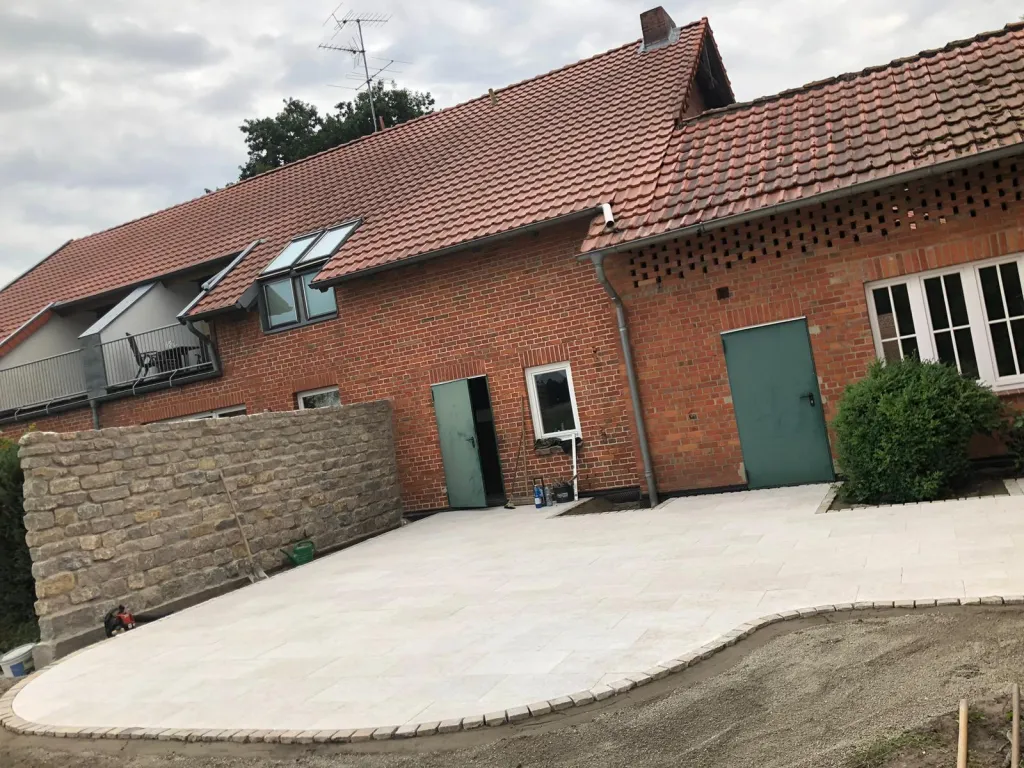 Terrasse aus hellem Pflaster an einem Klinkerhaus