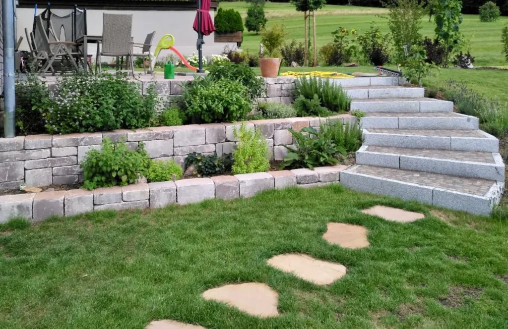 Terrassierter Hanggarten mit Natursteinmauern und Trittplatten