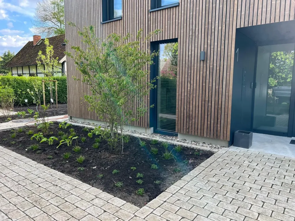 Vorgartenbeet mit Pflasterkante an einem Holzhaus