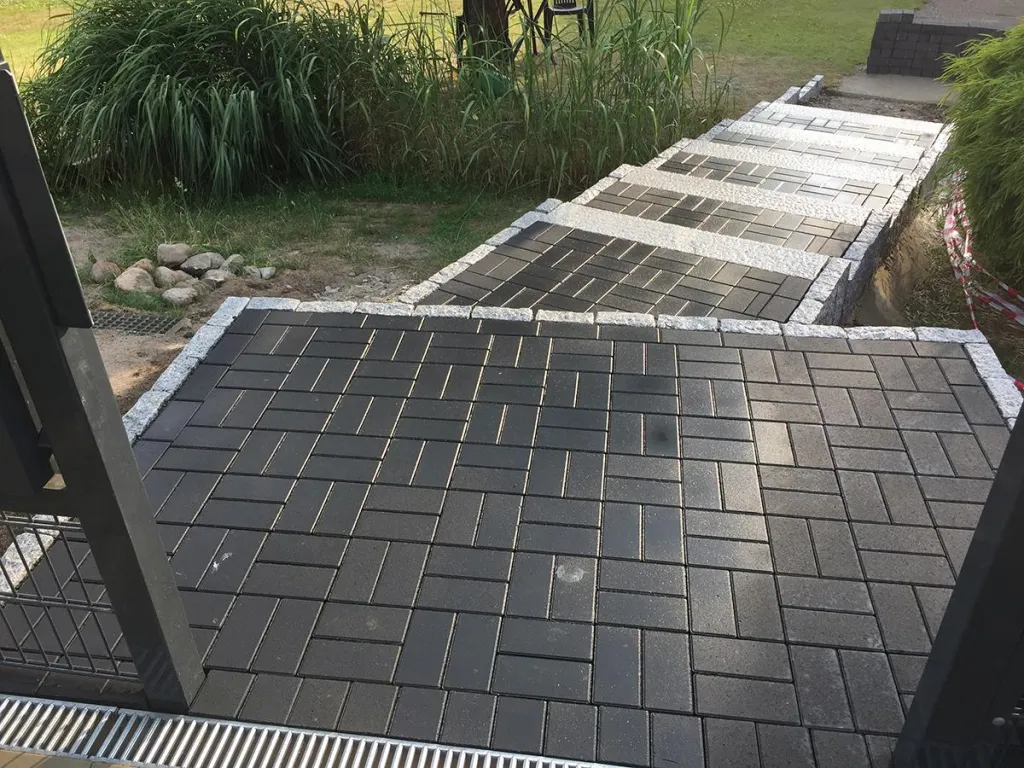 Weg aus dunklem Betonpflaster mit heller Einfassung