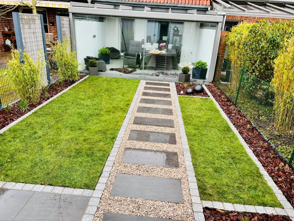 Weg aus Trittplatten und Kies zur überdachten Terrasse